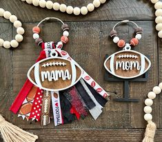 two necklaces that say mama and football are hanging on a wooden table with tassels