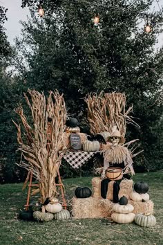 two scarecrows made out of hay and pumpkins