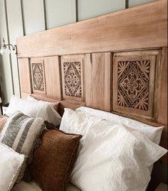 a wooden headboard with pillows on top of it in a bed room next to a window