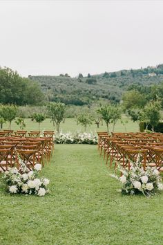 an outdoor ceremony setup with wooden chairs and flowers