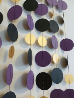 purple and black paper circles hanging from strings on a white wall with string attached to it