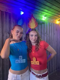 two young women standing next to each other in front of a wooden wall with colorful lights