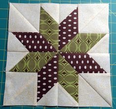 a green and brown star quilt block sitting on top of a cutting board