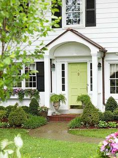 a white house with green front door surrounded by flowers