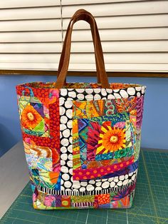 a multicolored bag sitting on top of a cutting board next to a window