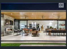 an open living room and dining area in a house with wood ceilinging, large windows, and sliding glass doors