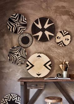 several black and white plates hanging on the wall above a wooden table with stools