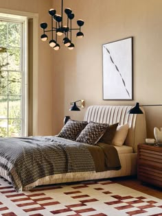 a bed sitting in a bedroom under a chandelier next to a large window