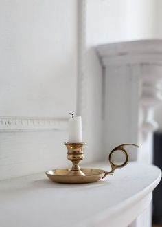 a white mantle with a gold candle holder on it