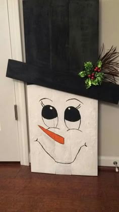 a cardboard snowman with a black hat and nose painted on it's face