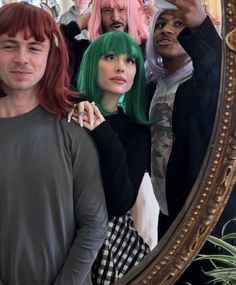 a group of people standing in front of a mirror with their hair dyed pink and green