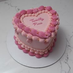 a heart shaped cake with pink frosting and gold decorations