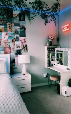 a bedroom with a bed, desk and pictures on the wall above it is lit by neon lights