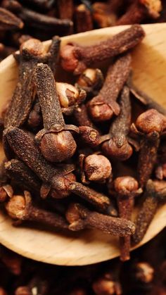 a wooden spoon filled with cloves on top of a table