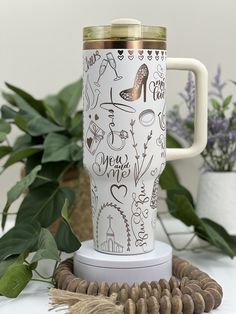 a white coffee mug sitting on top of a table next to some nuts and plants