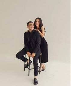 a man and woman sitting on a chair posing for the camera with their arms around each other