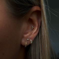 a close up of a woman's ear with three different piercings on it