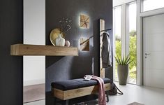 a black and white room with a bench, coat rack, potted plant and mirror