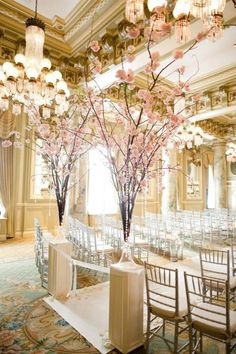 an elegant ballroom set up for a wedding with chandeliers and flowers in vases