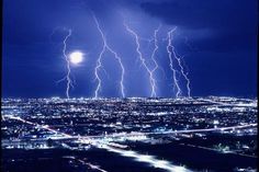 lightning strikes over the city at night time