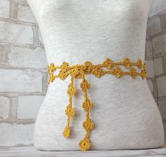 a yellow crocheted belt is shown on a mannequin's torso