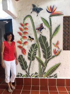 a woman standing in front of a wall with flowers and butterflies painted on the side