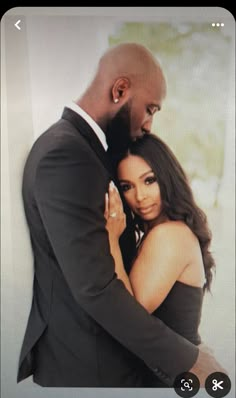 a man and woman embracing each other in front of a white wall with the caption's name on it