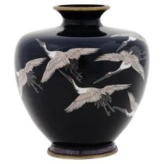 a black vase with white cranes painted on it