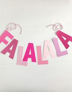 the word famal spelled out in pink and pink letters on a white background with string