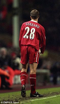 a soccer player is standing on the field with his hands in his pockets and looking down