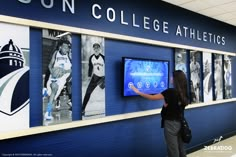 Person uses custom touchscreen Athletic Facility Design, College Hallway, College Branding, Social Media Wall, Higher Education Design, Athletic Branding, Media Installation, High School Design, Educational Design