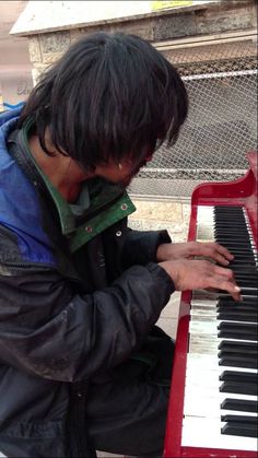 a young man is playing the piano outside