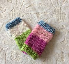 two knitted mittens sitting on top of a white tablecloth covered in lacy doily