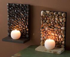 two lit candles sitting next to each other near rocks and stones on a wall with a canadian flag