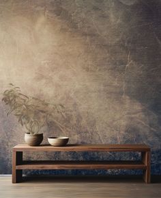 two bowls sit on a wooden table in front of a wall