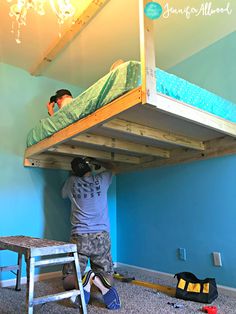 two men are working on a bunk bed in a room with blue walls and carpet