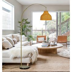 a living room filled with furniture and a tall lamp on top of a wooden table