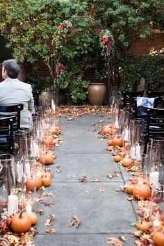 an outdoor ceremony with candles and pumpkins on the aisle for guests to sit down