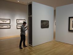 a woman looking at artwork on display in an art gallery with white walls and wooden floors