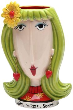 a ceramic vase with a woman's face painted on the side and flowers in her hair