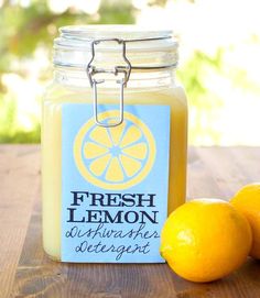 two lemons sitting on a table next to a jar of fresh lemon water with the label