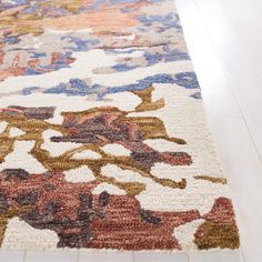 a multicolored rug on the floor in a room with hard wood floors and white walls