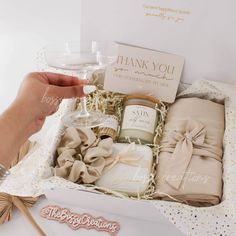 a person holding a wine glass next to a gift box filled with personal care items