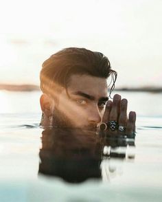 a man is floating in the water with his hands on his face and looking into the distance