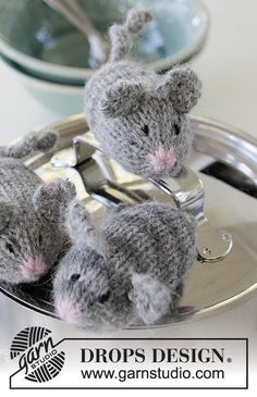 three stuffed mice sitting on top of a silver tray next to spoons and forks