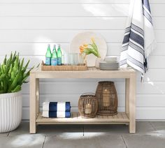 a table with towels, plates and bottles on it next to a potted plant