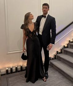 a man and woman in formal wear standing next to each other on the stairs at an event