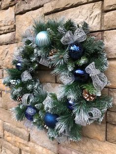 a christmas wreath hanging on the side of a brick wall with blue and silver ornaments