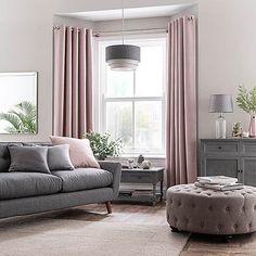 a living room filled with furniture and pink curtains