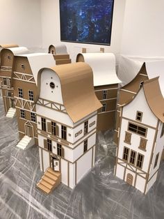 several cardboard model houses are on display in front of a projector screen that is projected onto the wall